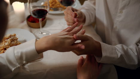 man hands wearing engagement ring romantic dinner close up. two lovers proposal