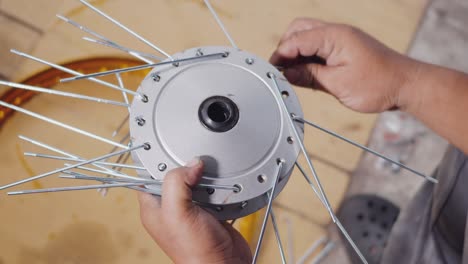 técnico hombre trabajando rueda de motocicleta tiene rayos tejer en mecánico nueva rueda de acero