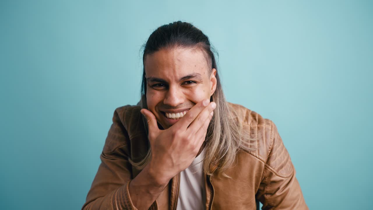 Giovane uomo con i capelli lunghi che passa dallo stress a un sorriso giocoso