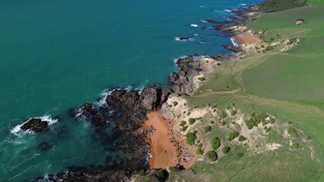 Pequeña-Playa-De-Arena-Roja-Rodeada-De-Oscuros-Acantilados,-Costa-Este-De-Nueva-Zelanda,-Katiki-Point