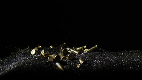 closeup of 22 long rifle ammunition bullets falling on bullet grains in slow motion