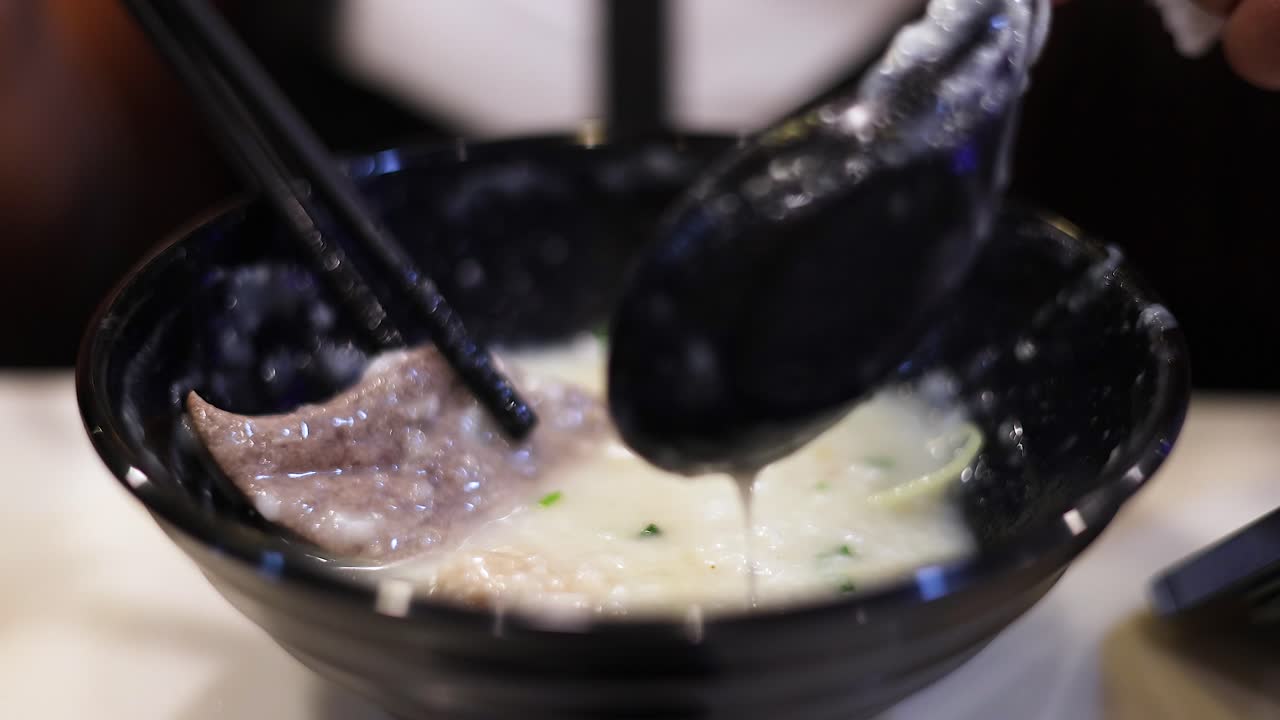 Spoon stirring congee in a black bowl
