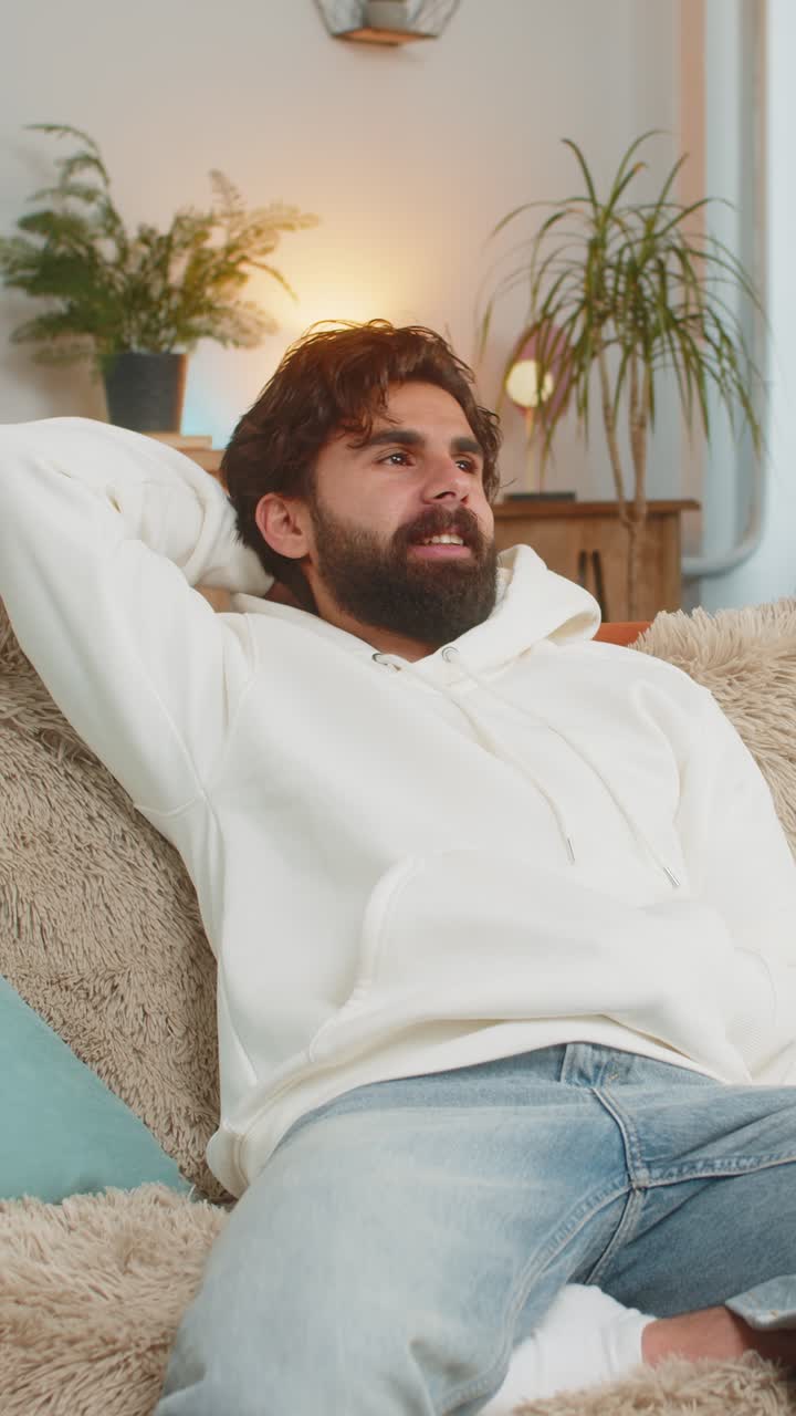 hombre indio feliz sentado en el sofá cerrando la computadora portátil y relajándose después de terminar el trabajo en la sala de estar