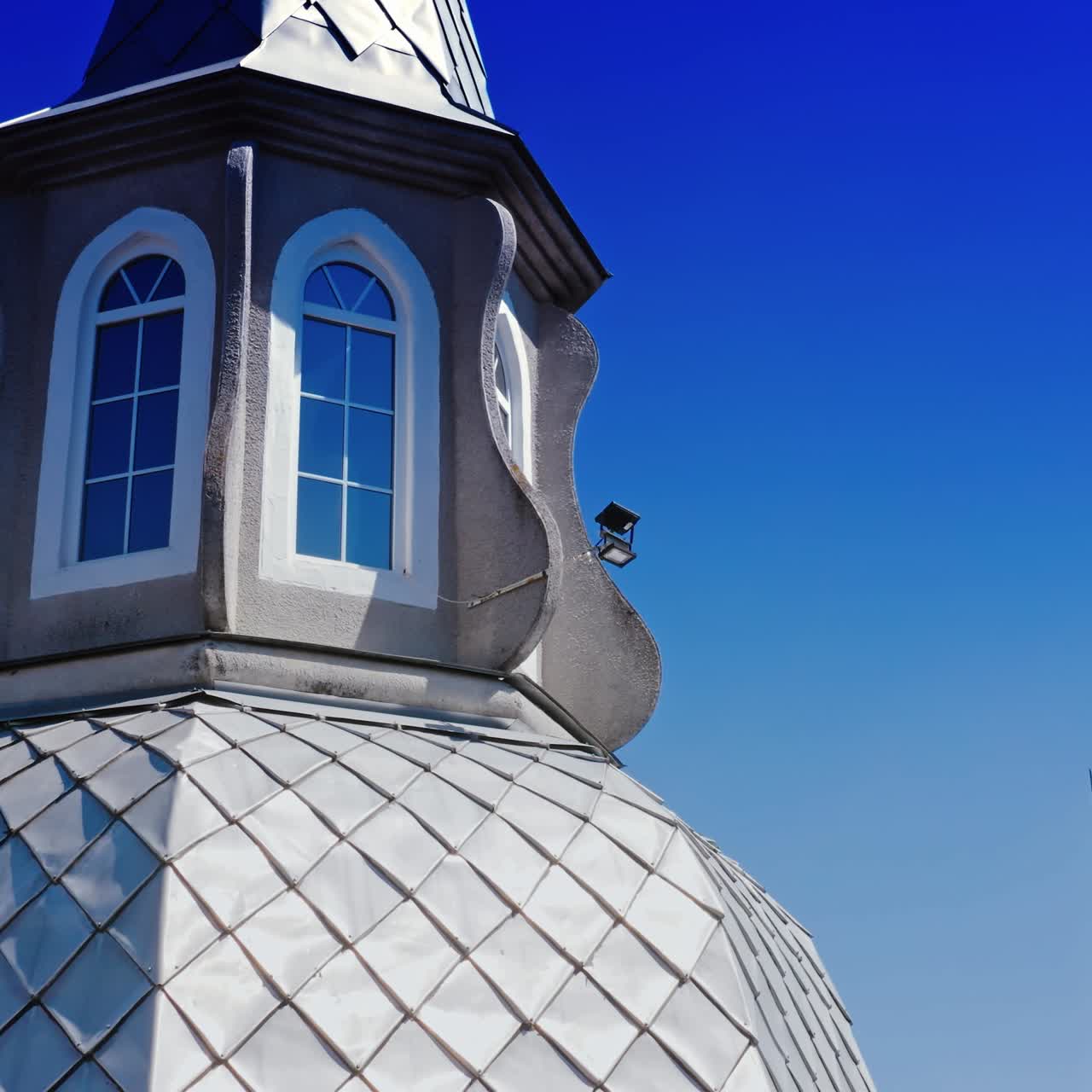 Facade of catholic church. Beautiful exterior of the catholic church with new windows on blue sky background. Close-up. Camera moving down.