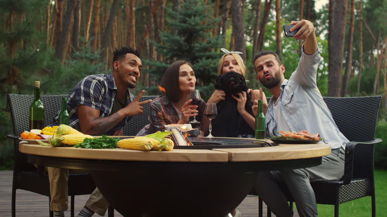 Amici allegri in posa per la fotocamera dello smartphone in giardino