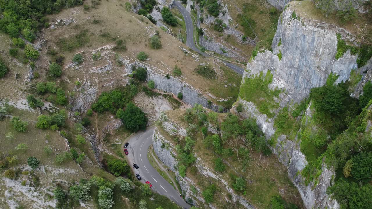 Aerial view following the road twisting through the limestone cliff formations at Cheddar gorge in the Mendip Hills, Somerset, UK