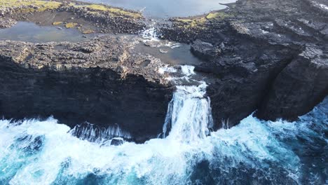 circular drone footage of the bøsdalafossur waterfall near the leitisvatn lake, aka the floating lake, on the vagar island in the faroe islands