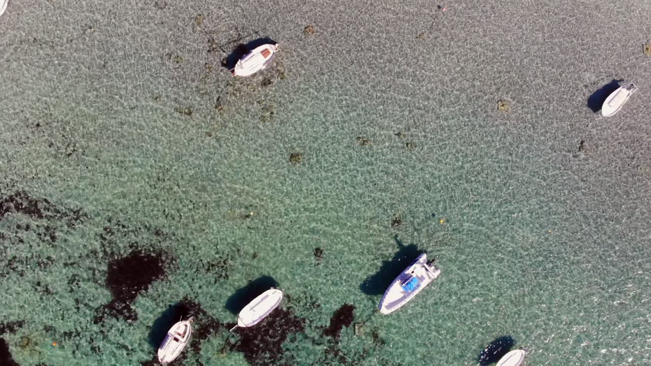 Drone footage of small boats anchored in shallow water from above