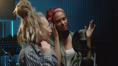 close up of the young two charming female singers recording a duet while singing a song in the microphone in the sound studio