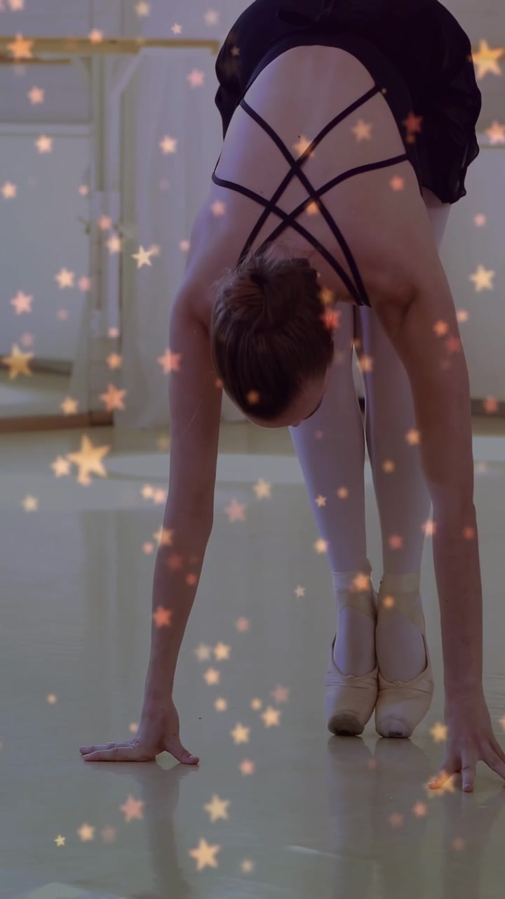 Video verticale: Ballerina che allaccia le scarpette da punta e poi si alza sulle punte per il riscaldamento, con stelle che attraversano l'inquadratura.