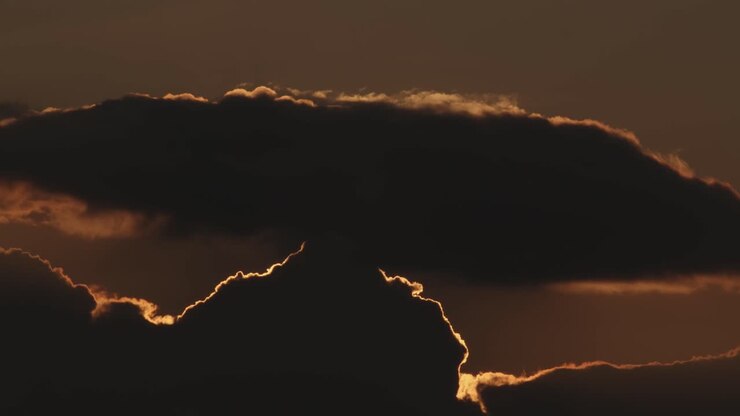 Tramonto rosso e arancione dietro nuvole scure, inquadratura ampia e statica
