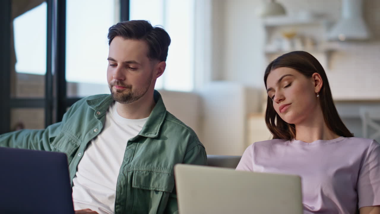 Remote workers typing computers at living room interior closeup. Man yawning