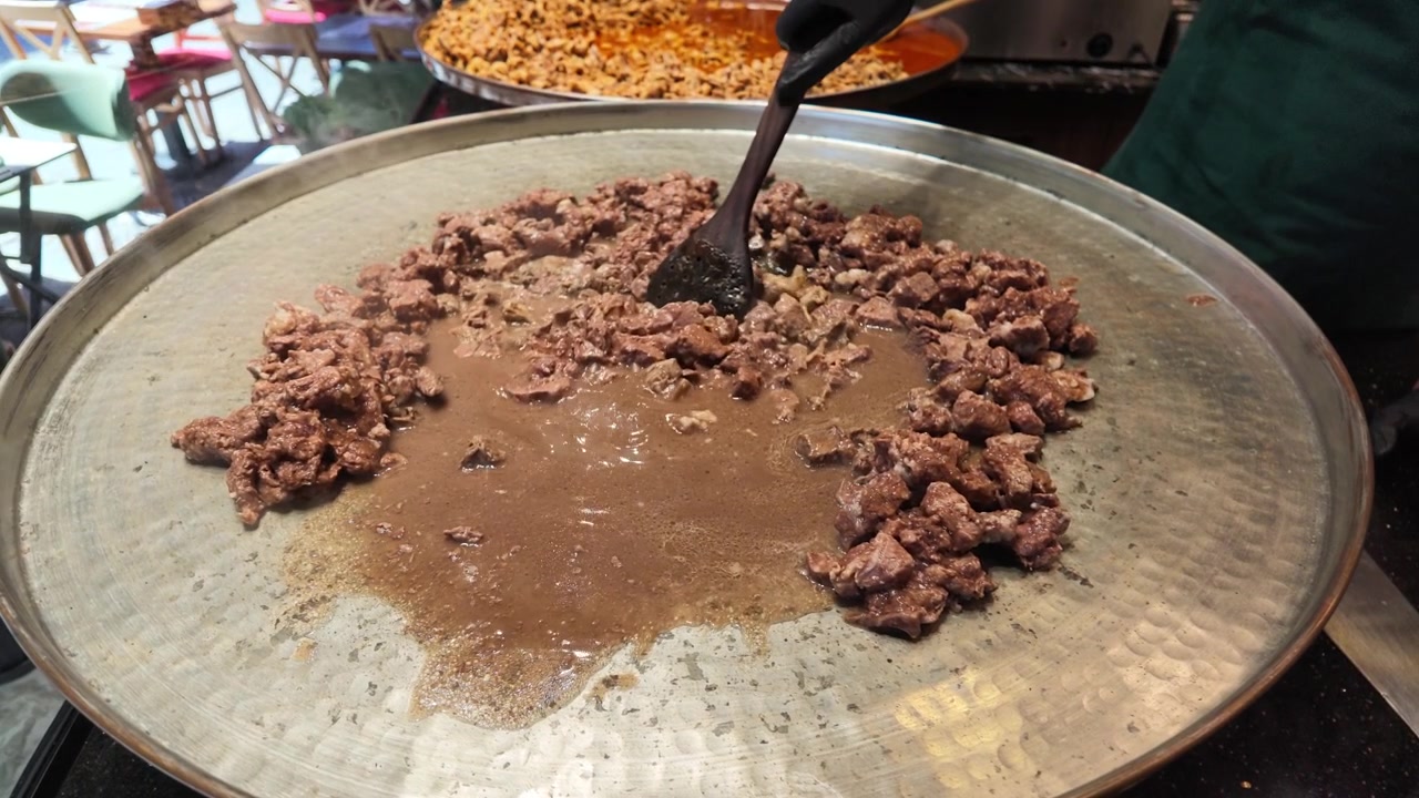Chef che cucina carne in una grande padella tradizionale
