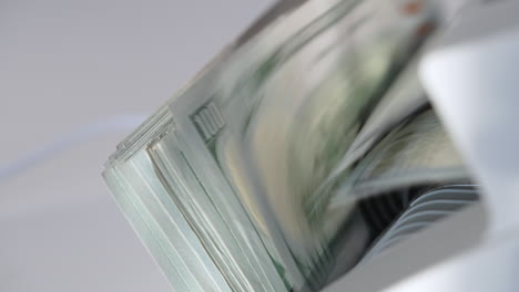 american dollar bills of hundred denomination rotated in cash machine. apparatus counts and then stops. close up.