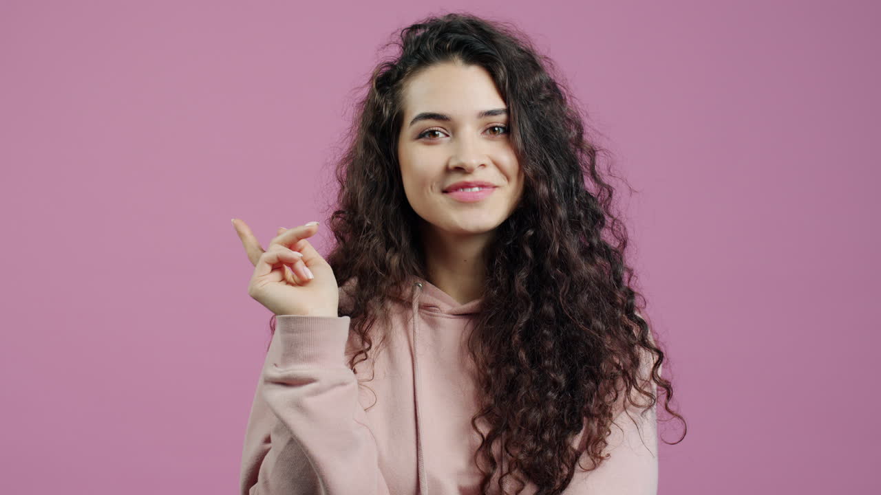 Woman with curly hair wearing a pink hoodie