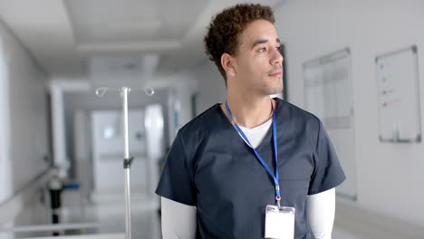 porträt eines glücklichen männlichen arztes aus zwei rassen, der in einem krankenhauskorridor einen schuppen trägt, kopierraum, slowmotion