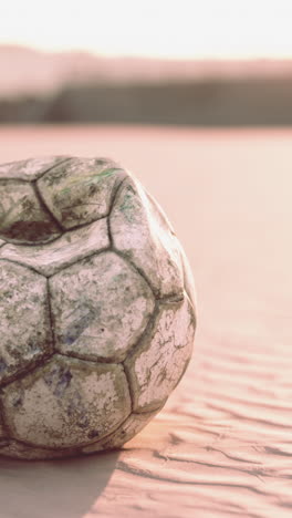 una pelota de fútbol vintage en una playa al atardecer