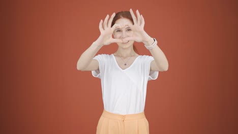 woman making heart sign at camera.