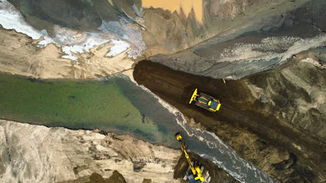 Machinery-for-sediment-diversion-in-a-pond,-with-mountain-backdrop-at-dusk,-aerial-view