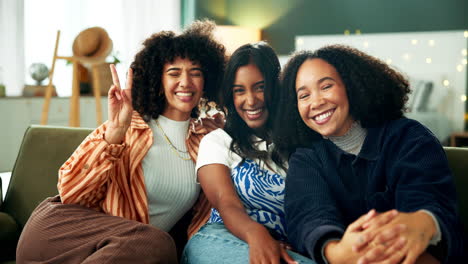 three happy diverse women friends sitting on a couch