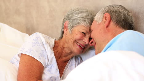 Happy-senior-couple-lying-in-bed-touching-heads