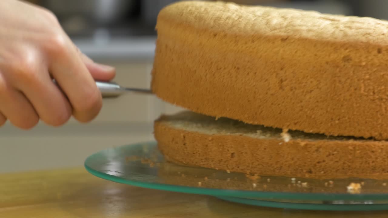 Close-up das mãos de uma mulher cortando um biscoito assado para fazer um bolo doce.