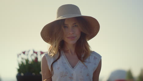 mujer rubia sensual con sombrero de sol mirando a la cámara en un brillante día de verano afuera.