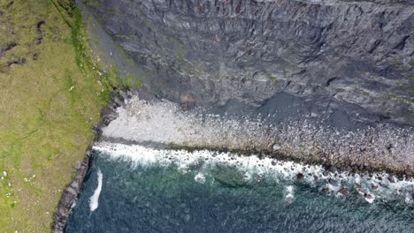 Ireland-The-Cliffs-Of-Moher,-panning-shot-from-the-beach-at-the-base-of-the-cliffs-to-the-top