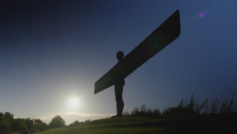 angel of the north silhouetted against a dark blue sky, low sun