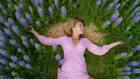 young woman resting peacefully in a field of purple lupine flowers