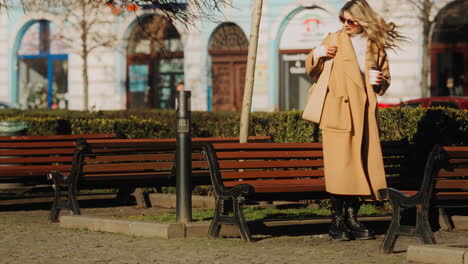 mujer rubia bastante elegante caminando y luego sentada sola en un banco público al aire libre para leer un libro, estilo callejero disparo cinematográfico