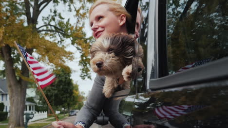 woman and dog and us flag in car window