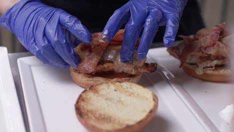 poner pollo y tocino encima del pan de hamburguesa