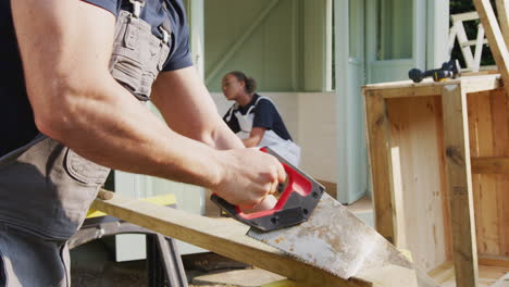 male carpenter with female apprentice building outdoor summerhouse in garden