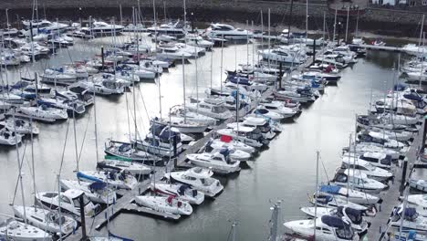 scenic luxurious waterfront harbour apartment village yachts and sailboats under mountain coastline low left orbit aerial view