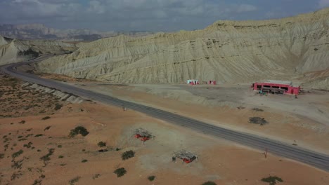 aerial of empty road and truck stop surrounded by weathered hills at hingol national park in balochistan