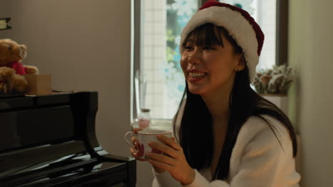 two pretty asian twin sisters sit by the piano and have a talk in warm cosy environment at home on christmas day