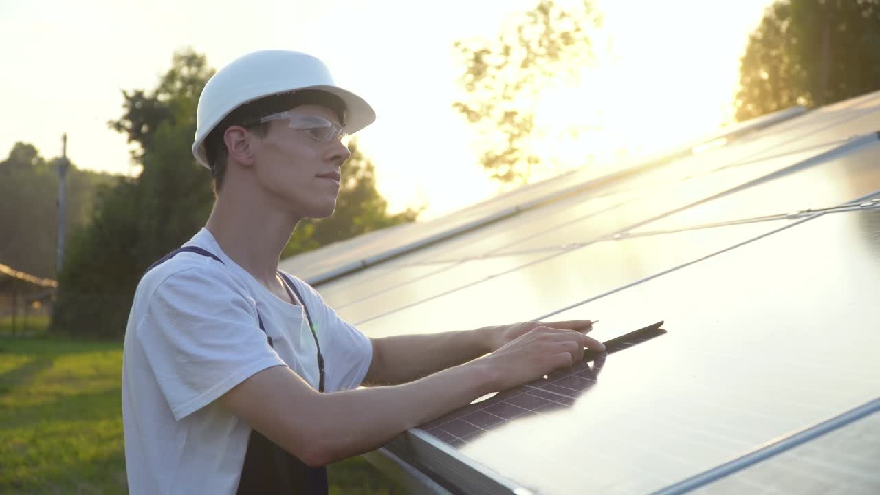 Solar panel technician working with solar panels. Engineer in a uniform with a tablet checks solar panels productivity. Alternative energy concept