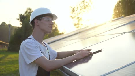 solar panel technician working with solar panels. engineer in a uniform with a tablet checks solar panels productivity. alternative energy concept