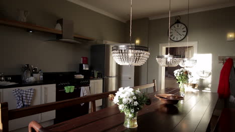 Large-kitchen-banquet-table-with-crystal-pendant-lights-and-bouquets-of-flowers-and-a-range-cooker