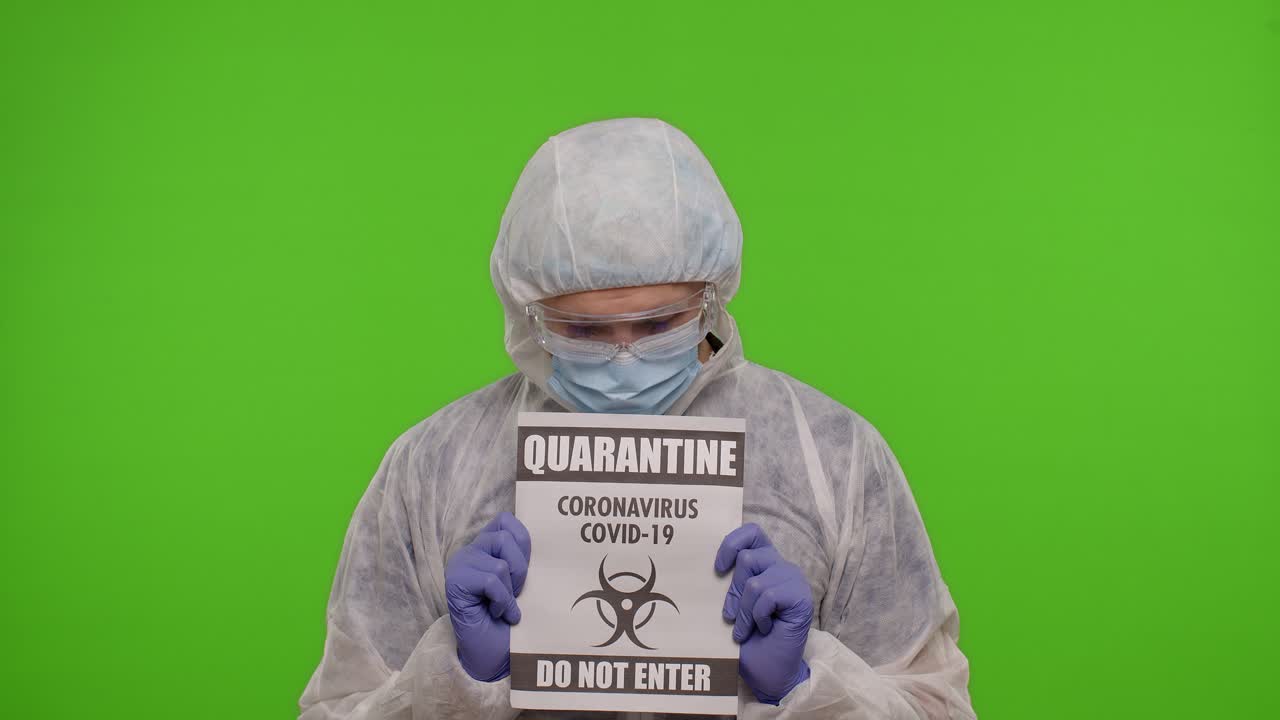 Un uomo in tuta anticontaminazione che tiene un cartello di quarantena