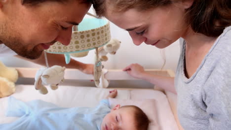 Happy-parents-watching-over-baby-son-in-crib-