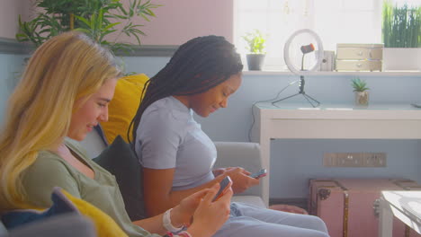 group of multi-cultural teenage girl friends with mobile phones hanging out in bedroom at home