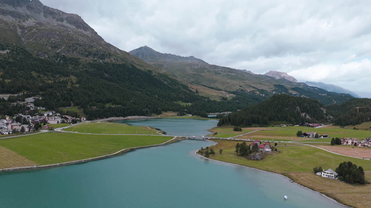 Serene lake near Silvaplana with mountains and clouds in the background