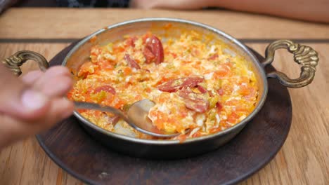 primer plano de un plato turco de desayuno llamado menemen, un plato de huevos, tomates y salchichas