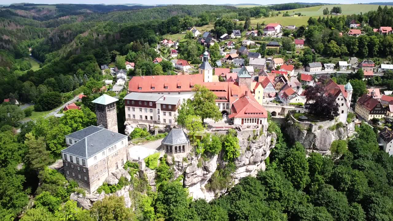Drone ascending vertically up with view on ancient castle and village on a hilltop on a bright beautiful day in Europe