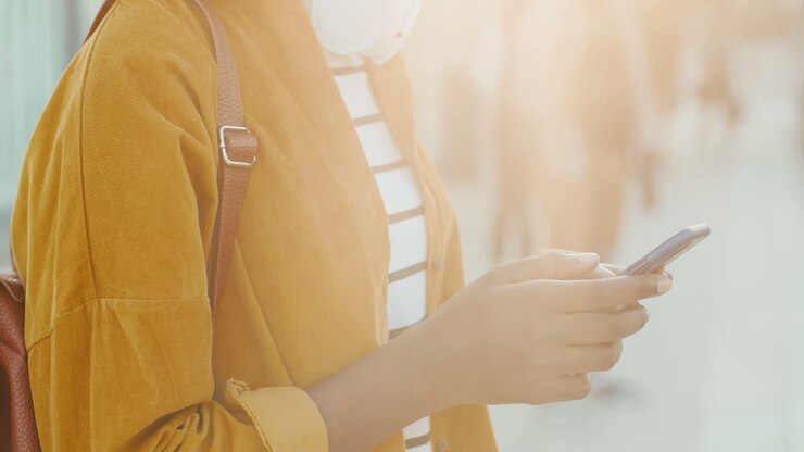 Le mani di una giovane viaggiatrice afroamericana che invia un messaggio sullo smartphone alla stazione dei treni.