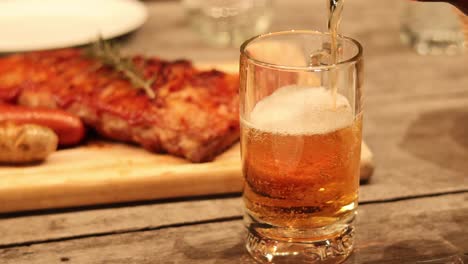 beer poured into glass next to delicious ribs