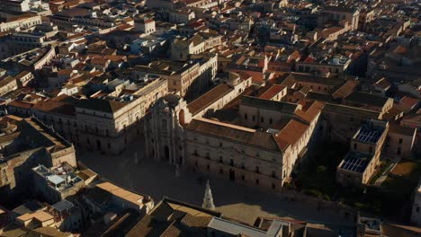 Drone-ascent-over-Syracuse,-showcasing-historic-buildings-and-cathedral,-culminating-in-breathtaking-coastal-horizon-with-sea