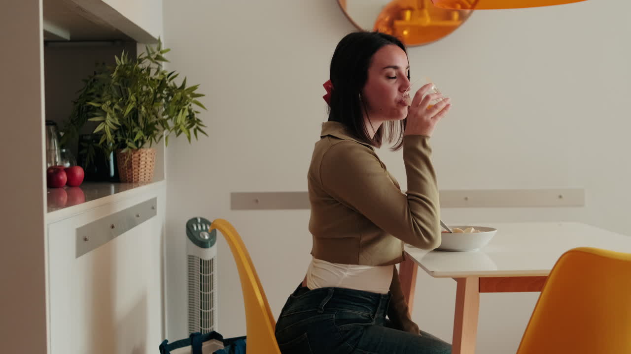 Side view of Young Woman Drinking Orange Juice in Kitchen